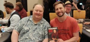 Greg Raymer and Paul Beitelspacher posing with Raymer's poker book at the Mixed Game Festival at Resorts World in Las Vegas, Nevada.